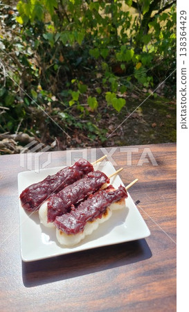 在溫暖的陽光下,於戶外享用春季日式甜點,如紅豆糰(甜豆沙團子)。 在溫暖的陽光下,於戶外享用春季日式甜點,如紅豆糰(甜豆沙團子)。 138364429