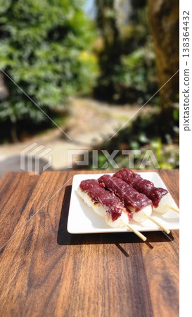在溫暖的陽光下,於戶外享用春季日式甜點,如紅豆糰(甜豆沙團子)。 在溫暖的陽光下,於戶外享用春季日式甜點,如紅豆糰(甜豆沙團子)。 138364432