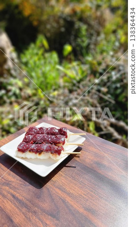 在溫暖的陽光下,於戶外享用春季日式甜點,如紅豆糰(甜豆沙團子)。 在溫暖的陽光下,於戶外享用春季日式甜點,如紅豆糰(甜豆沙團子)。 138364434
