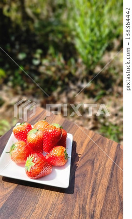 Bright red strawberries served on a plate bathed in bright sunlight. 138364442