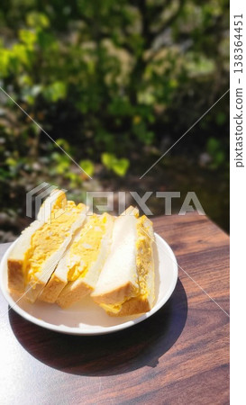 Enjoy a thick-cut egg sandwich outdoors in the dappled sunlight. Enjoy a thick-cut egg sandwich outdoors in the dappled sunlight. 138364451