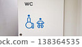 An accessible public restroom with wheelchair and baby changing symbols on the door and safety grab bars inside. Concepts of inclusivity, accessibility, and modern public infrastructure design. 138364535