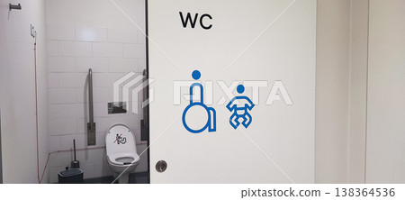 An accessible public restroom with wheelchair and baby changing symbols on the door and safety grab bars inside. Concepts of inclusivity, accessibility, and modern public infrastructure design. An accessible public restroom with wheelchair and baby changing symbols on the door and safety grab bars inside. Concepts of inclusivity, accessibility, and modern public infrastructure design. 138364536