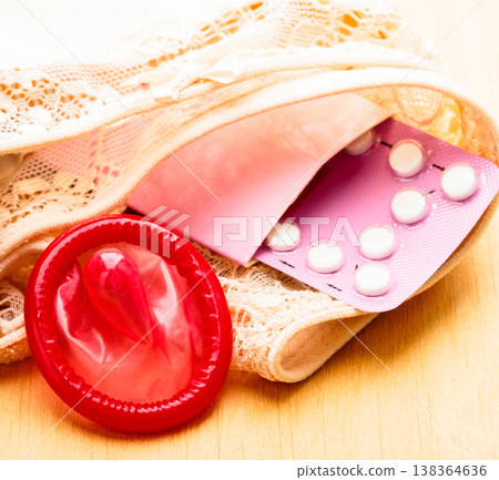 Oral contraceptive pills and condom on lace lingerie Oral contraceptive pills and condom on lace lingerie 138364636
