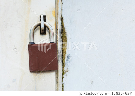 Closed padlock on the white metal door Closed padlock on the white metal door 138364657