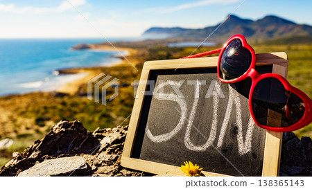 Black board with word sun against sea coast Black board with word sun against sea coast 138365143