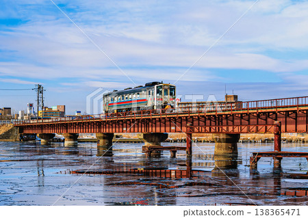 A local train reflected on the icy surface of the river; a winter bridge and its reflection. 138365471
