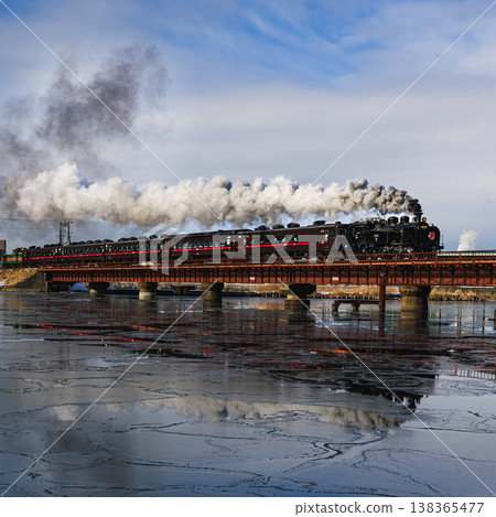SL 冬季沼澤地列車駛過一條冰封的河流,蒸汽機車行駛著,冒出白煙。 SL 冬季沼澤地列車駛過一條冰封的河流,蒸汽機車行駛著,冒出白煙。 138365477