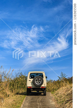 一輛越野車在廣闊的天空和雲朵的背景下行駛——這是一幅春日駕車的畫面。 138365500
