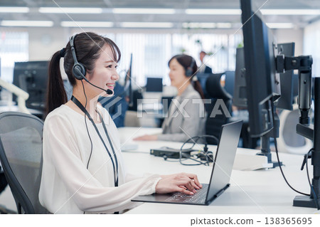 A smiling woman assisting customers at a call center. A smiling woman assisting customers at a call center. 138365695