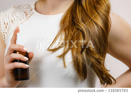 Woman applying hair cosmetic 138365783
