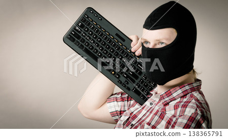 Man wearing balaclava holding keyboard Man wearing balaclava holding keyboard 138365791