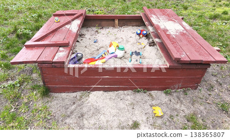 Wooden old sandbox with sliding cover filled with sand and colorful toys in a backyard, outdoor play area for children, summer leisure and family fun concept Wooden old sandbox with sliding cover filled with sand and colorful toys in a backyard, outdoor play area for children, summer leisure and family fun concept 138365807