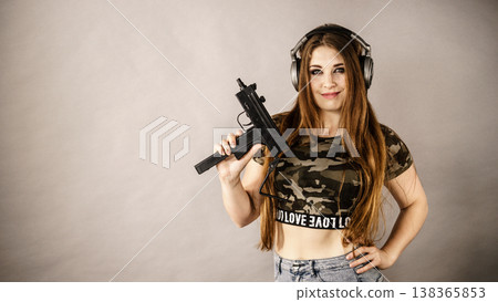 Woman wearing headphones holding gun Woman wearing headphones holding gun 138365853