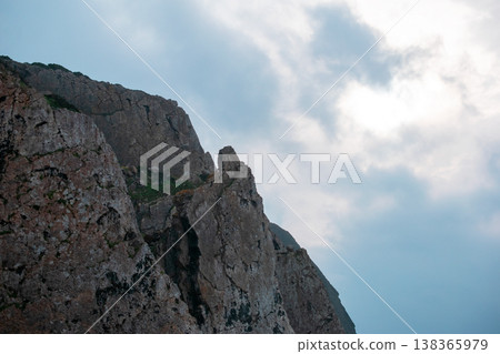 Rugged Cliff Face Under Cloudy Sky 138365979
