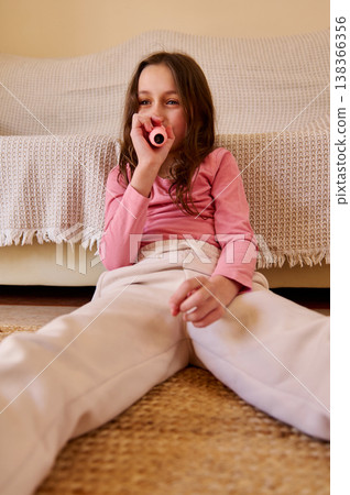 Young Girl Sitting On Floor With Pink Toy Kazoo Relaxing In Cozy Living Room 138366356