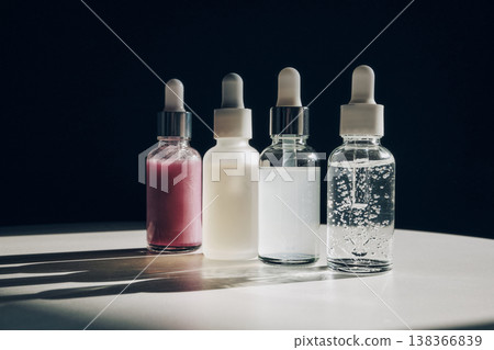 Four glass bottles with pipettes containing different cosmetic serums on table Four glass bottles with pipettes containing different cosmetic serums on table 138366839