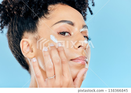 Beauty, studio portrait and woman with cream application of ointment, lotion or creme for skin hydration, wellness or skincare. Melasma treatment, face acne protection and model on blue background Beauty, studio portrait and woman with cream application of ointment, lotion or creme for skin hydration, wellness or skincare. Melasma treatment, face acne protection and model on blue background 138366845