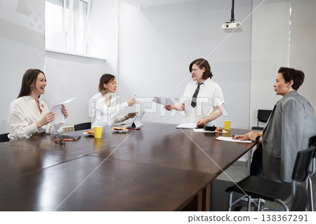 Team of businesswomen in white shirts reviewing notes and laptops during meeting in modern office. Reviewing, notes, businesswomen, meeting, laptops, office. Team of businesswomen in white shirts reviewing notes and laptops during meeting in modern office. Reviewing, notes, businesswomen, meeting, laptops, office. 138367291
