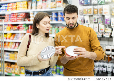 Couple of shoppers are choosing canned fish in food store Couple of shoppers are choosing canned fish in food store 138367343