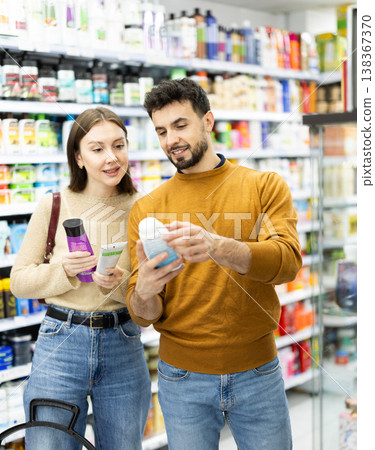 Married couple buyers chooses shampoo or shower gel in household chemicals store 138367370