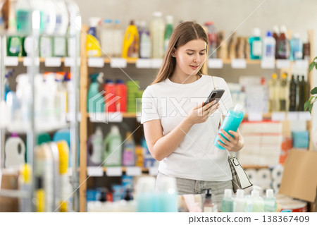 Checking expiration date of shampoo or shower gel - female shopper scans QR code on label of shampoo using smartphone 138367409