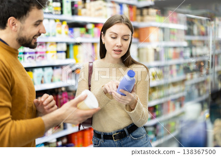 Married couple buyers chooses shampoo or shower gel in household chemicals store 138367500