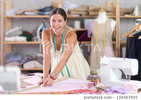 Young female dressmaker drawing on textile in sewing workshop Young female dressmaker drawing on textile in sewing workshop 138367605