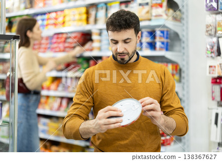 Man in supermarket search and select product tin can 138367627