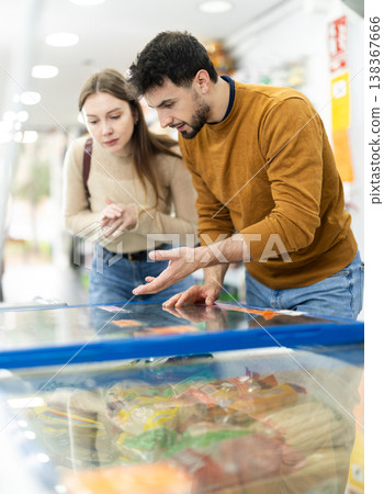 Couple spends time in store, looking for necessary goods and get out from refrigerator 138367666