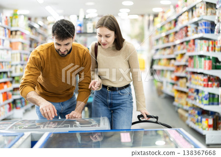 Couple spends time in store, looking for necessary goods and get out from refrigerator 138367668