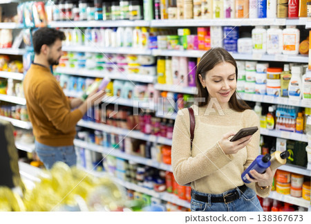 Woman get acquainted with good, scan QR code, take reading label using phone camera in shop 138367673