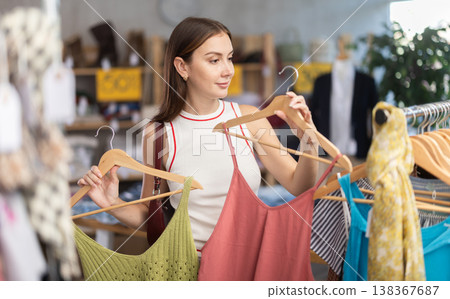 Young woman browsing summer dresses in local store Young woman browsing summer dresses in local store 138367687