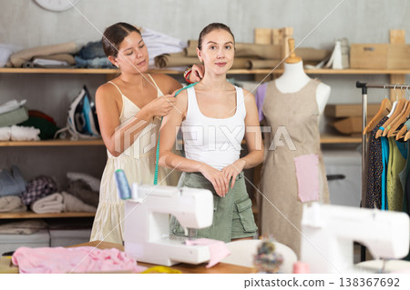 Young female dressmaker measuring woman client Young female dressmaker measuring woman client 138367692