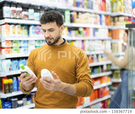 Young man choosing body and hair care products in supermarket Young man choosing body and hair care products in supermarket 138367719