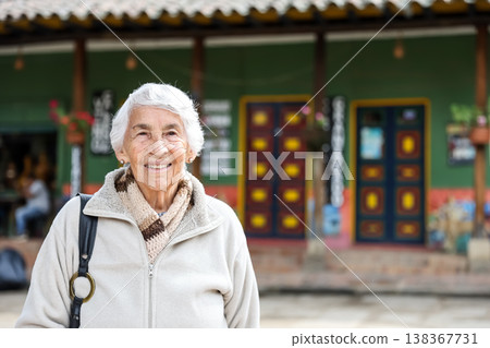 Happy senior lifestyle concept. Senior woman at the central square of the beautiful small town of Raquira. The city of pots in Colombia. Happy senior lifestyle concept. Senior woman at the central square of the beautiful small town of Raquira. The city of pots in Colombia. 138367731