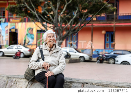 Happy senior lifestyle concept. Senior woman at the central square of the beautiful small town of Raquira. The city of pots in Colombia. 138367741