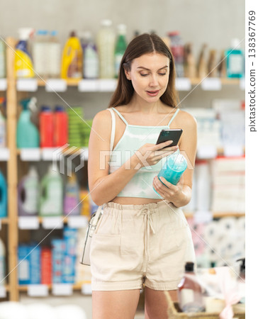 Woman scanning hair shampoo on her phone in supermarket Woman scanning hair shampoo on her phone in supermarket 138367769