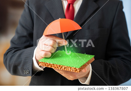 An umbrella over a plot of land symbolizes property insurance and protection. Legal safeguards secure ownership rights. Risk management ensures stability in real estate investments An umbrella over a plot of land symbolizes property insurance and protection. Legal safeguards secure ownership rights. Risk management ensures stability in real estate investments 138367807