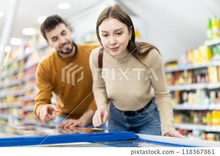 Couple spends time in store, looking for necessary goods and get out from refrigerator Couple spends time in store, looking for necessary goods and get out from refrigerator 138367861