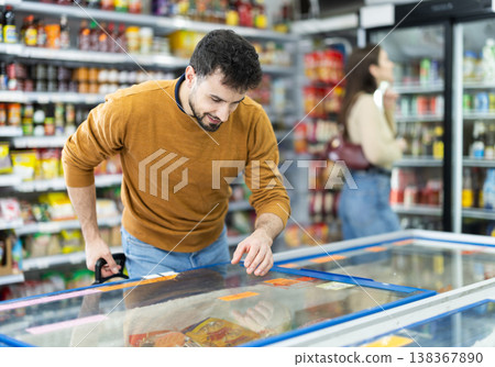 Man spends time in store, looking for necessary goods and get out from refrigerator Man spends time in store, looking for necessary goods and get out from refrigerator 138367890