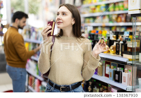 Young woman chooses perfume in store 138367910