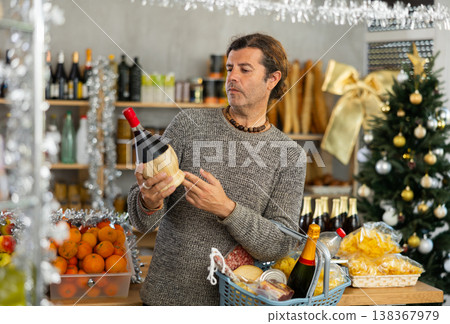 Man choosing wine in grocery store adorned for Christmas Man choosing wine in grocery store adorned for Christmas 138367979