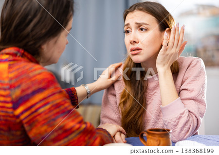 Woman complains to her friend about life while sitting at table with cups of tea Woman complains to her friend about life while sitting at table with cups of tea 138368199