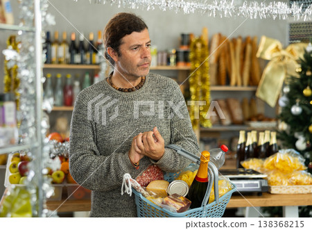 Customer with shopping basket browsing aisles of festive grocery store Customer with shopping basket browsing aisles of festive grocery store 138368215