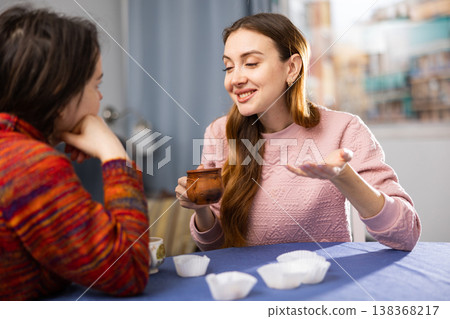 Two female friends drinking tea and talking at home Two female friends drinking tea and talking at home 138368217