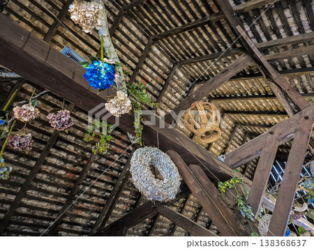 Rustic wooden ceiling with hanging colourful flower bouquets and wicker ornaments 138368637