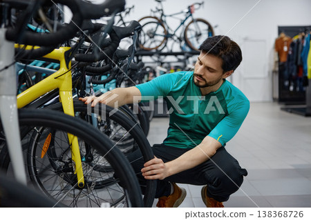 Skilled male technician thoroughly inspects bicycle wheel quality Skilled male technician thoroughly inspects bicycle wheel quality 138368726