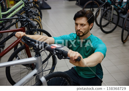Skilled male technician diligently evaluating fit and stance of bicycle handlebars in modern Skilled male technician diligently evaluating fit and stance of bicycle handlebars in modern 138368729