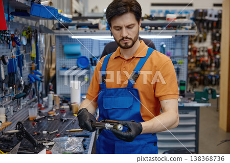 Skilled worker repairing bicycle hub in well-equipped neighborhood repair shop Skilled worker repairing bicycle hub in well-equipped neighborhood repair shop 138368736
